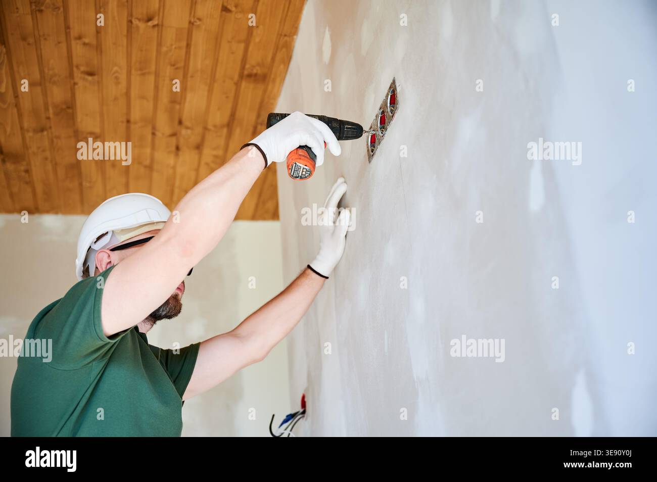 Electrician installing wall outlet with drill and securing electrical ...