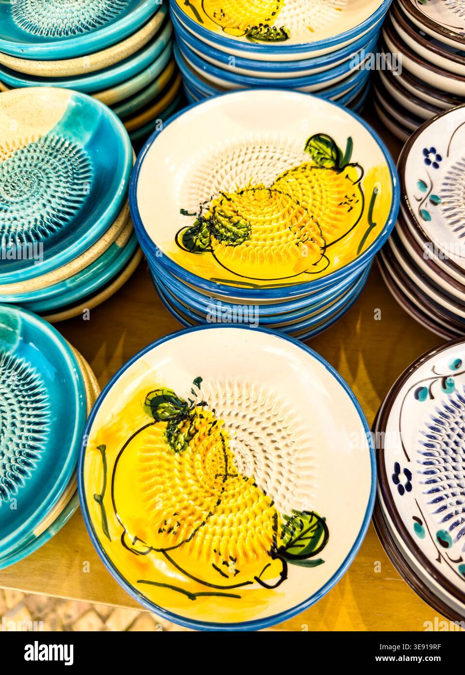 Stacks of traditional ceramic garlic and ginger grater plates with hand painted lemon designs at a market display - Smartphone Captured Stock Image