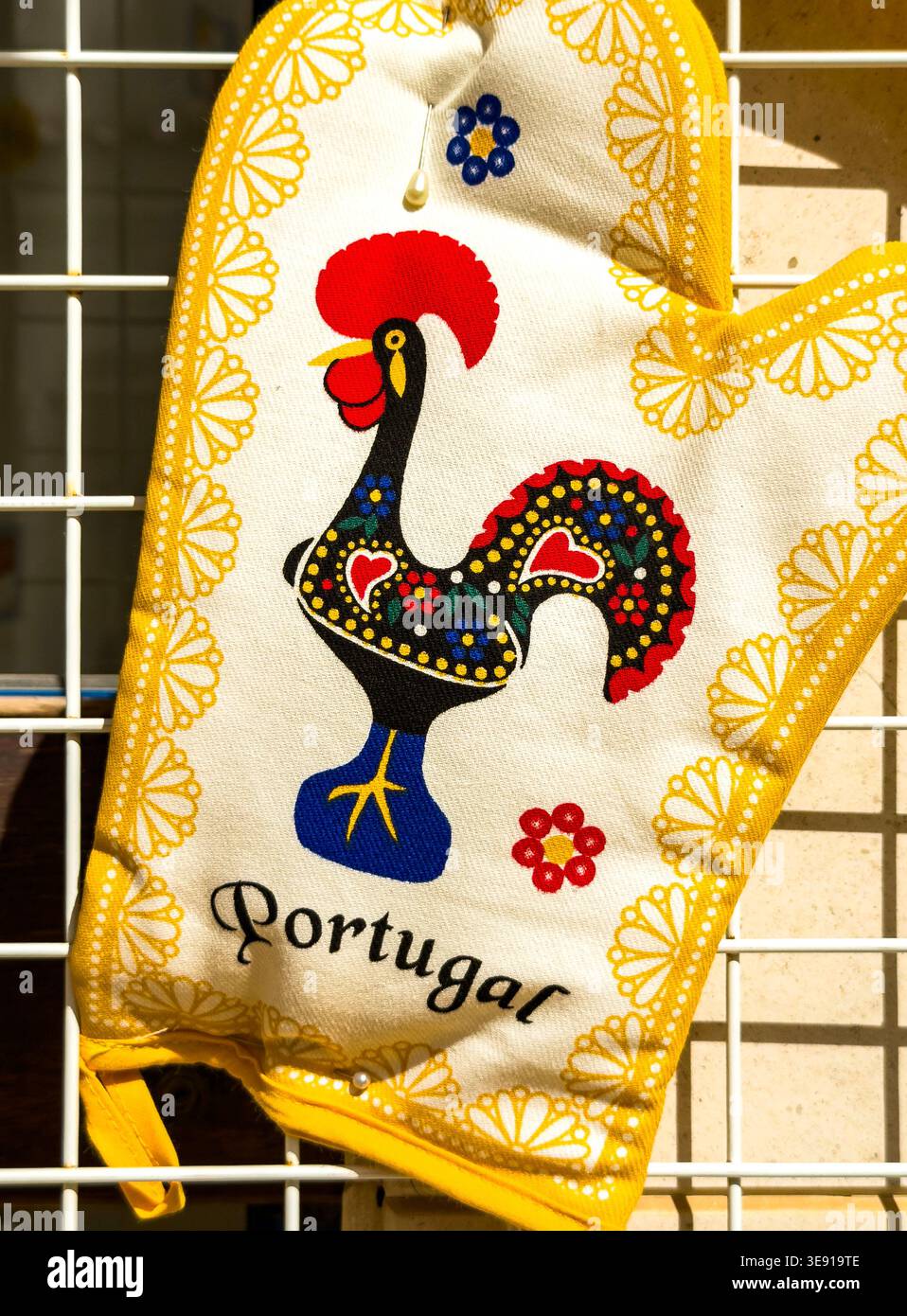 Traditional Portuguese oven mitt featuring the Rooster of Barcelos and Portugal text hanging on a display rack Stock Photo