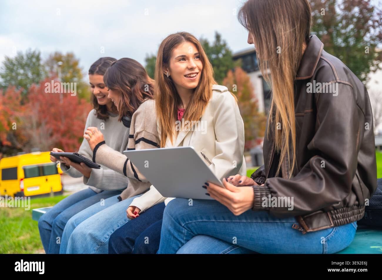 Female students collaborating outdoors using digital devices for education Stock Photo