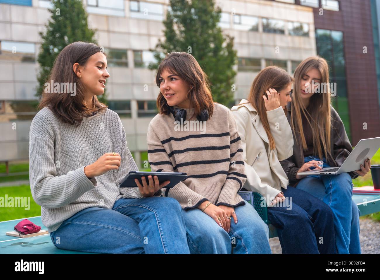 Young female student group discussing outdoors at university campus Stock Photo