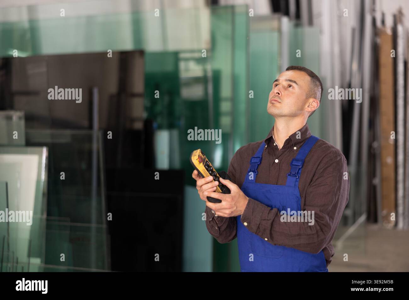 Worker using remote control to operate machinery in glass workshop Stock Photo