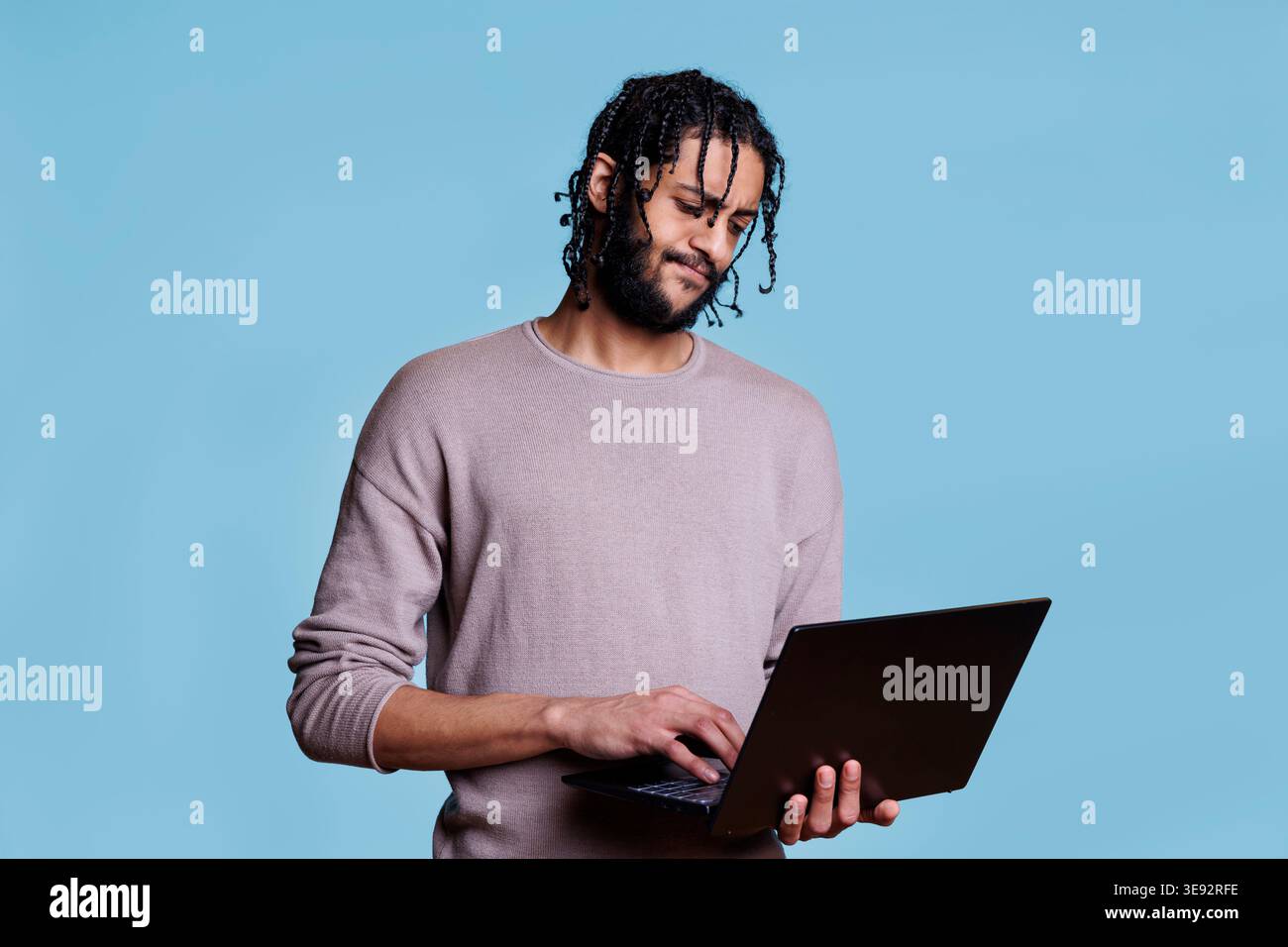 Thoughtful arab man analyzing software development while working on laptop. Young coder with pensive facial expression solving problem while programming app on portable computer Stock Photo