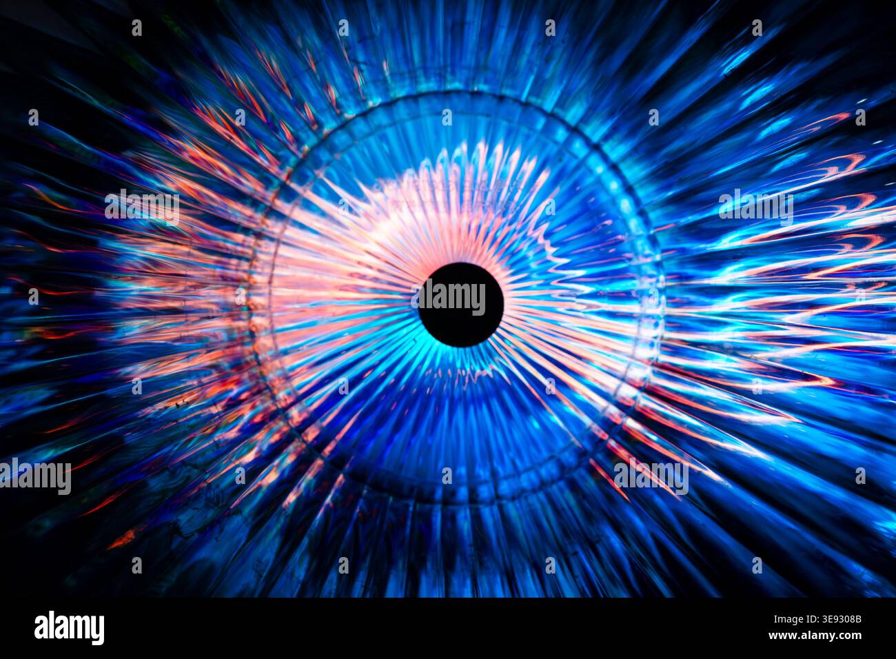 Circular abstract burst of bright blue and orange radiating neon rays forming an eye Stock Photo