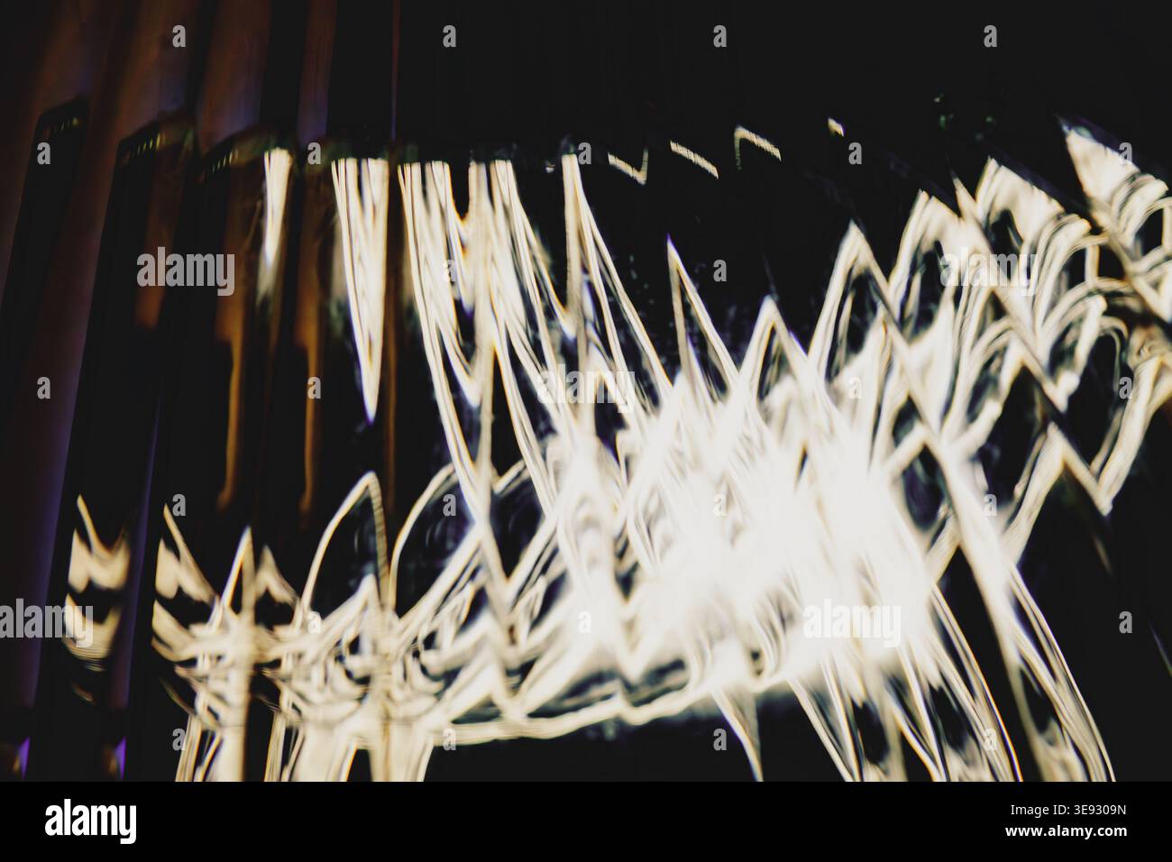 Golden abstract light trails forming sharp geometric zigzags over a dark background Stock Photo