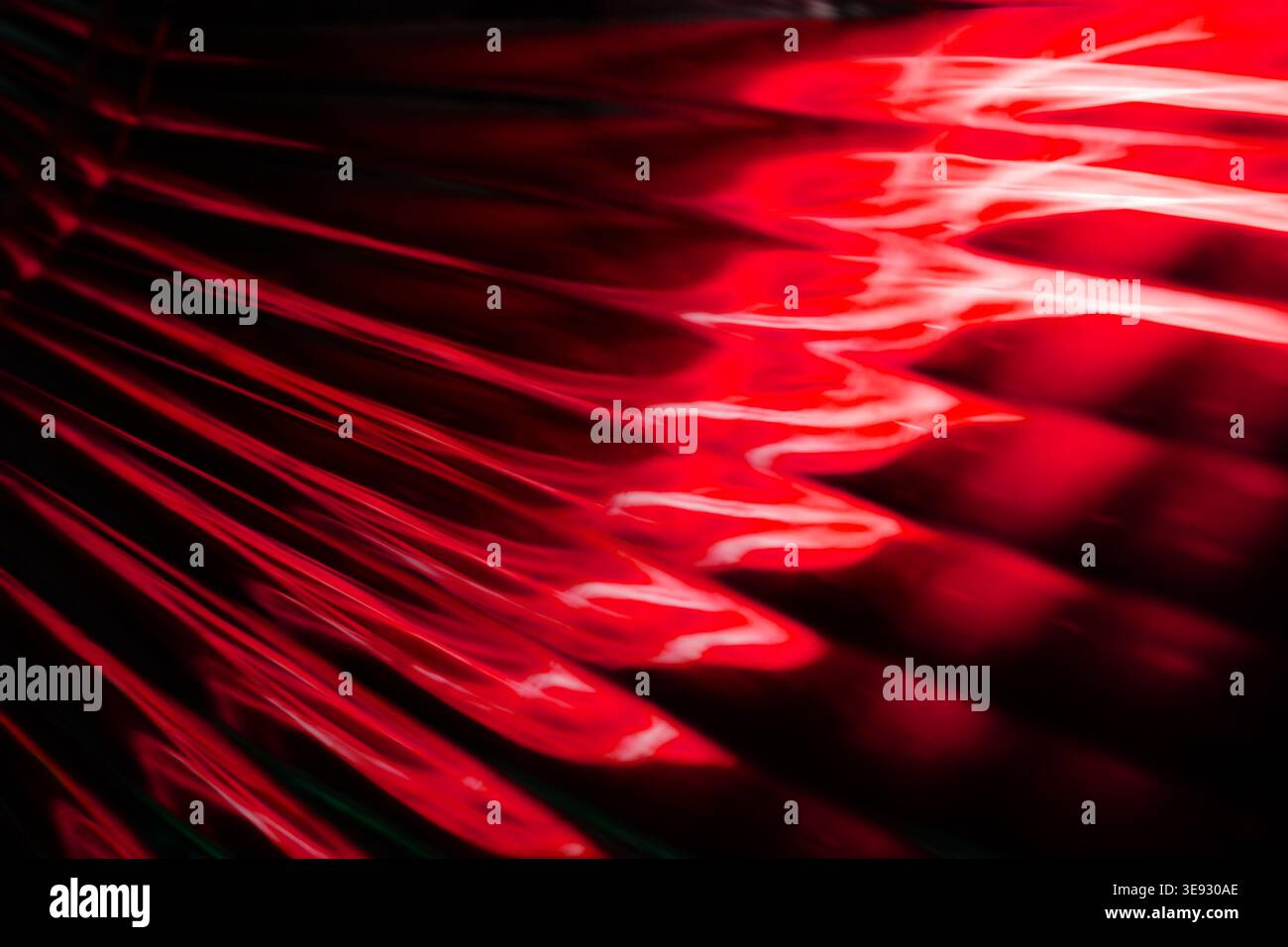 Deep red glowing abstract liquid waves creating a smooth modern background texture Stock Photo