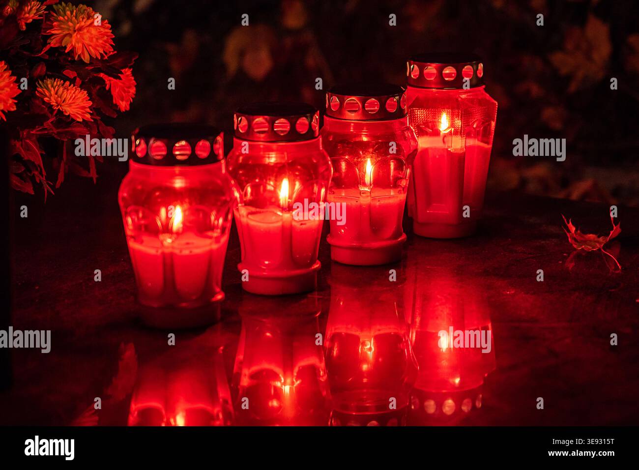 Grave candles burning brightly in a cemetery at night, honoring the memory of loved ones Stock Photo