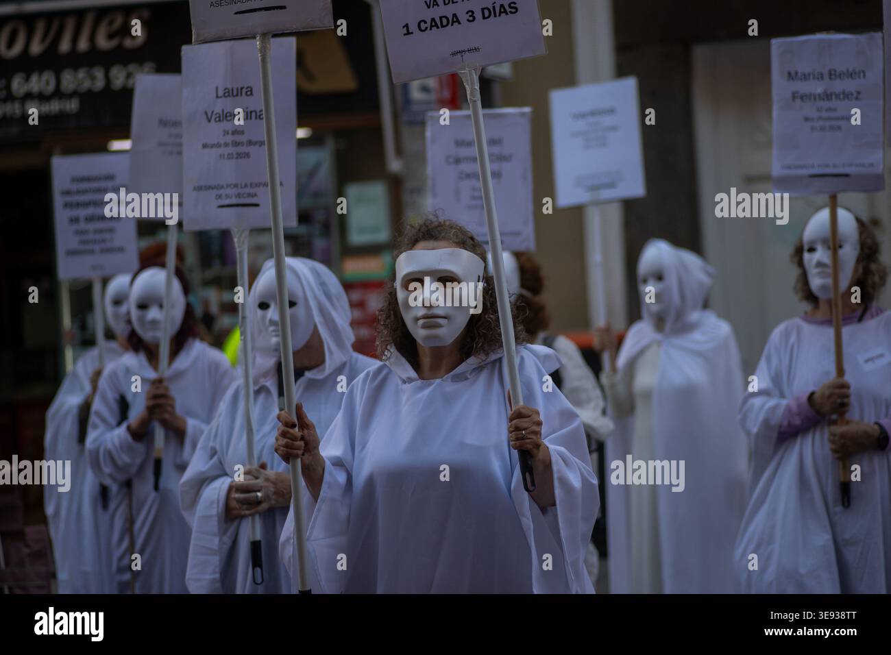 Women in white robes and masks hold placards during a demonstration ...