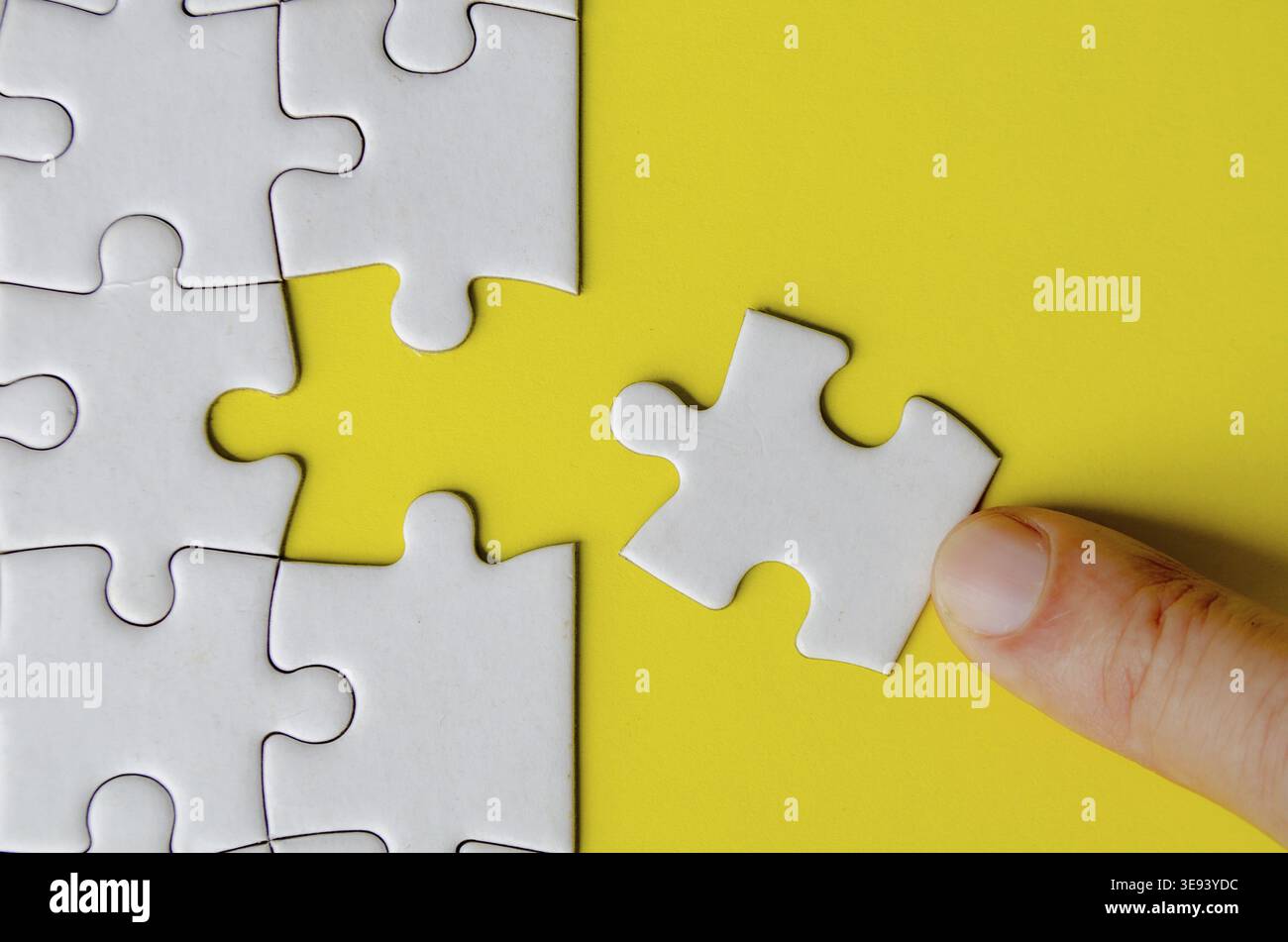 Hand fitting a missing white jigsaw pieces Stock Photo