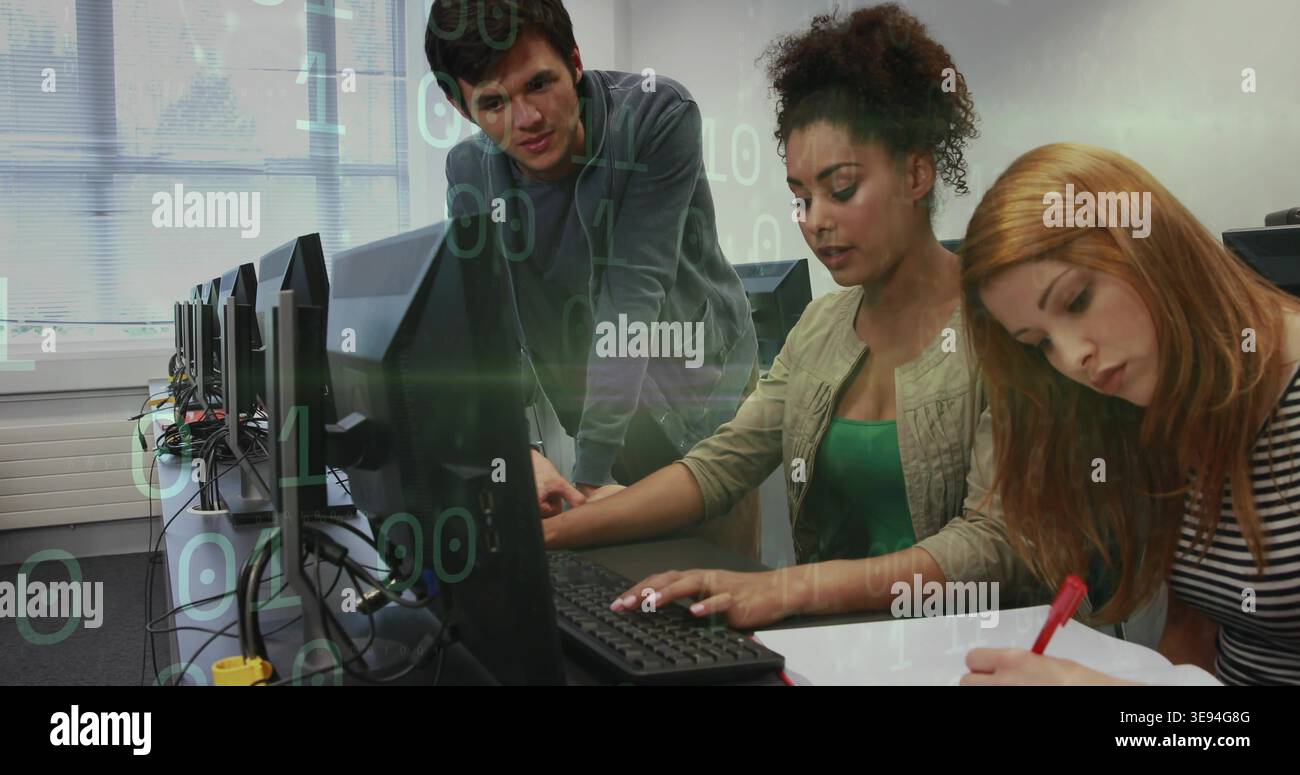 Typing trio collaborating on coding and notes in computer lab, with red pen, monitors and cables Stock Photo