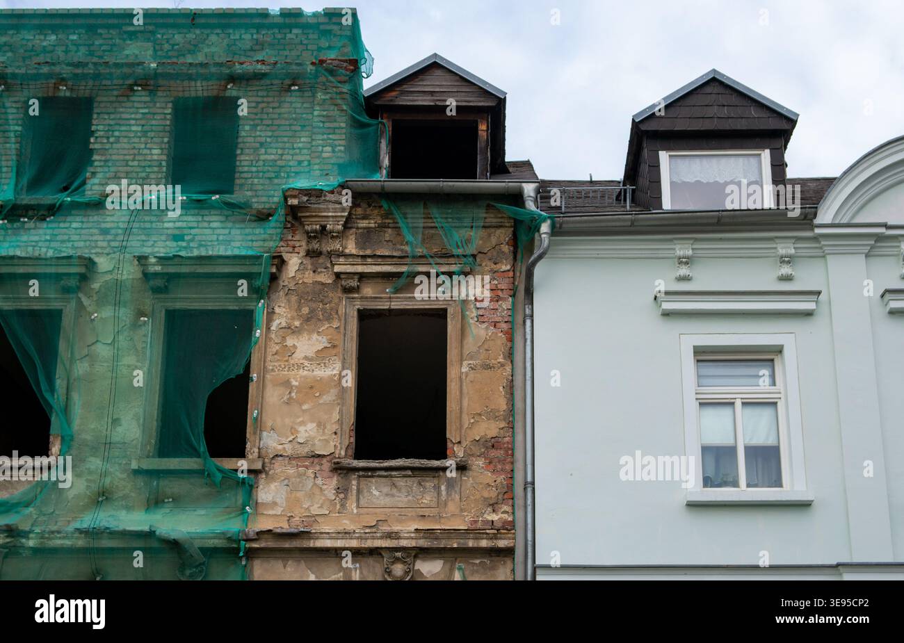 old abandoned house with a renovated house next to it to compare the contrast Stock Photo