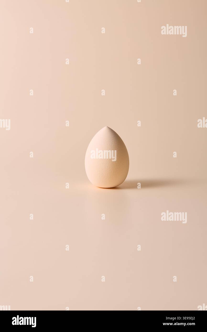 Minimal beige makeup sponge on neutral background Stock Photo