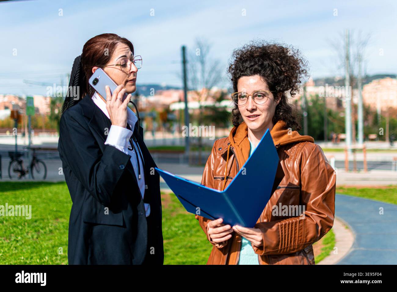 Business women collaborating outdoors discussing project details Stock Photo