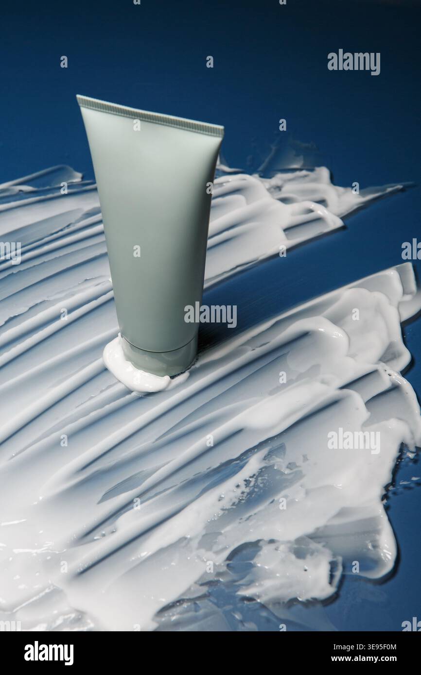 Skincare Tube on Cream Smear Blue Background Stock Photo