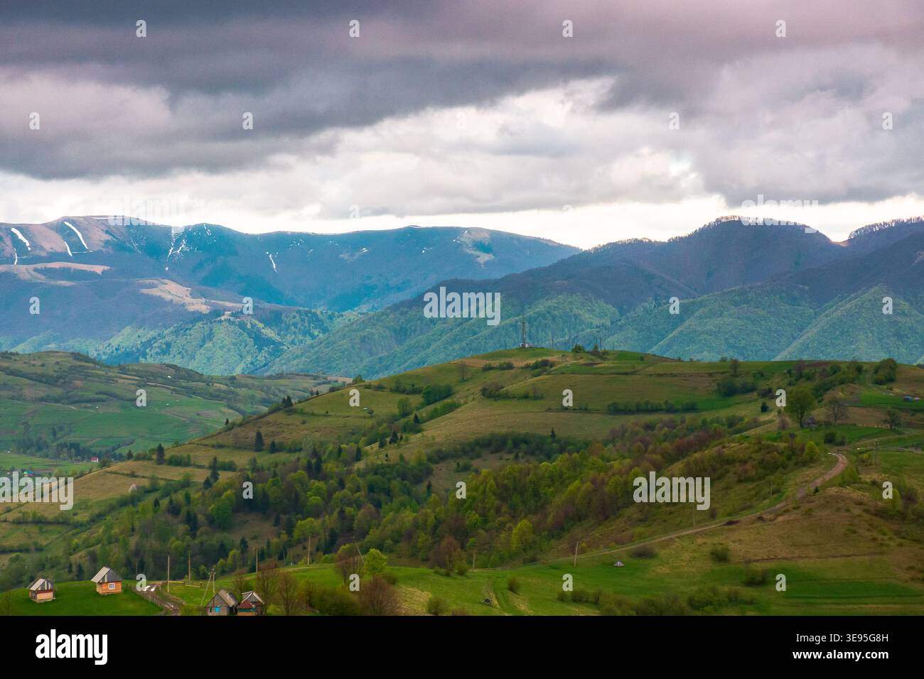 mountainous countryside scenery in the afternoon. gloomy sky view above the valley. green fields and trees on the hills. volatile nature scenery of ca Stock Photo