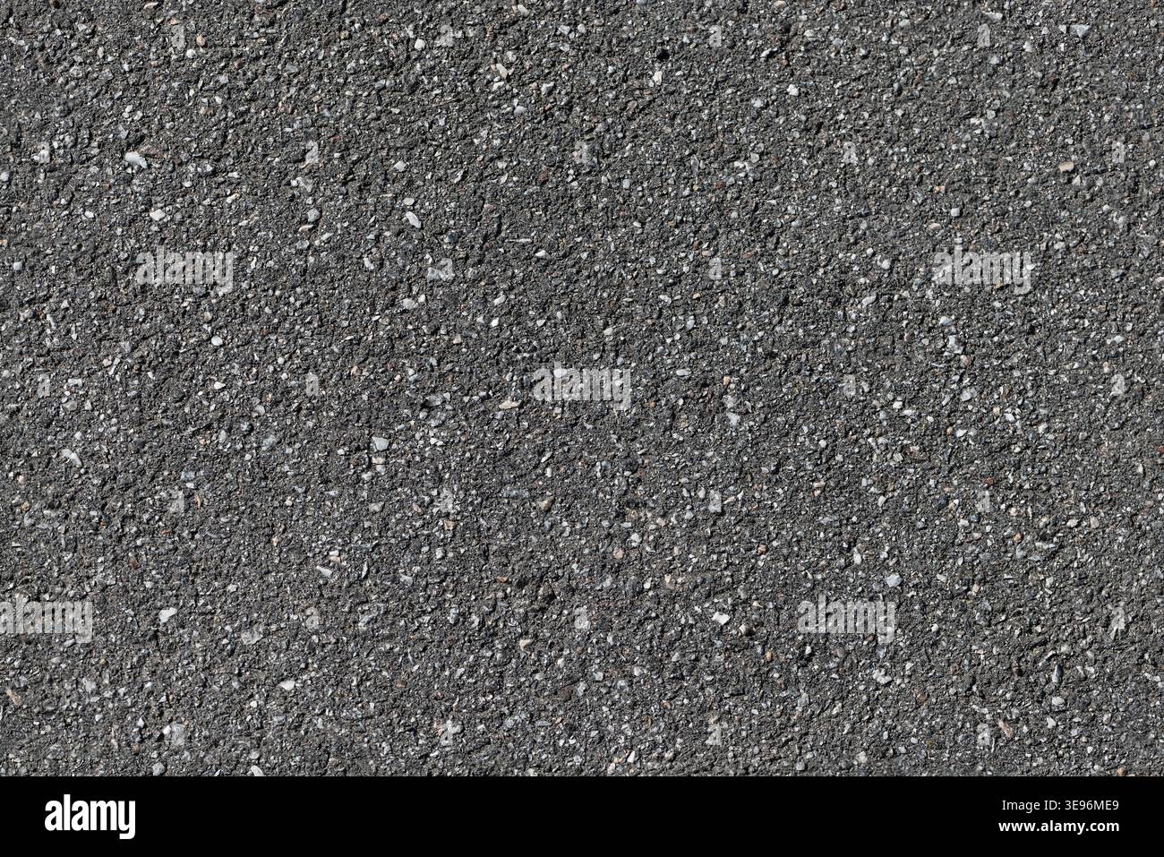Close-up view of coarse asphalt pavement showing granular gravel, dark road surface and subtle texture suitable as a seamless background or overlay fo Stock Photo