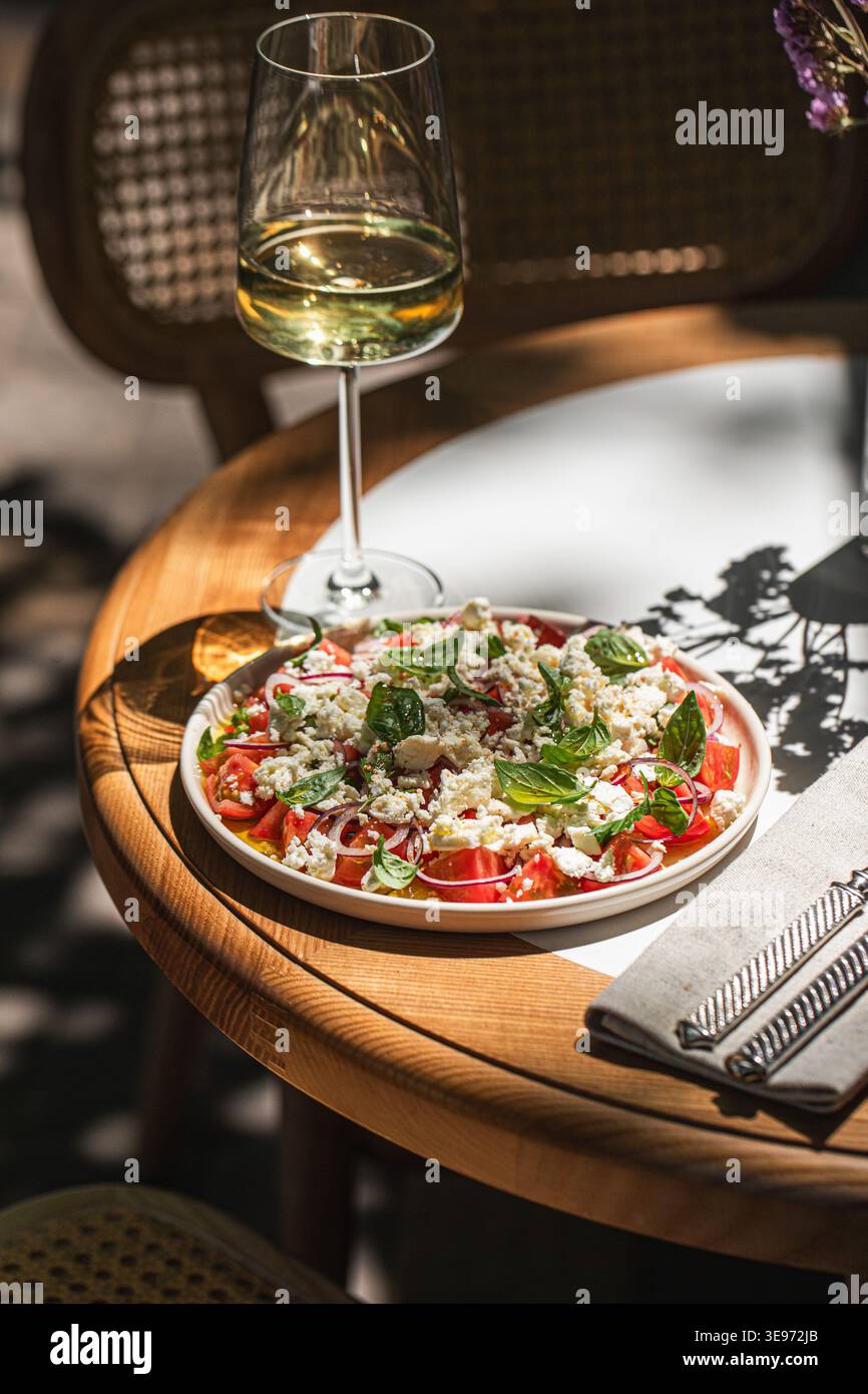 Mediterranean salad with wine on sunny table Stock Photo