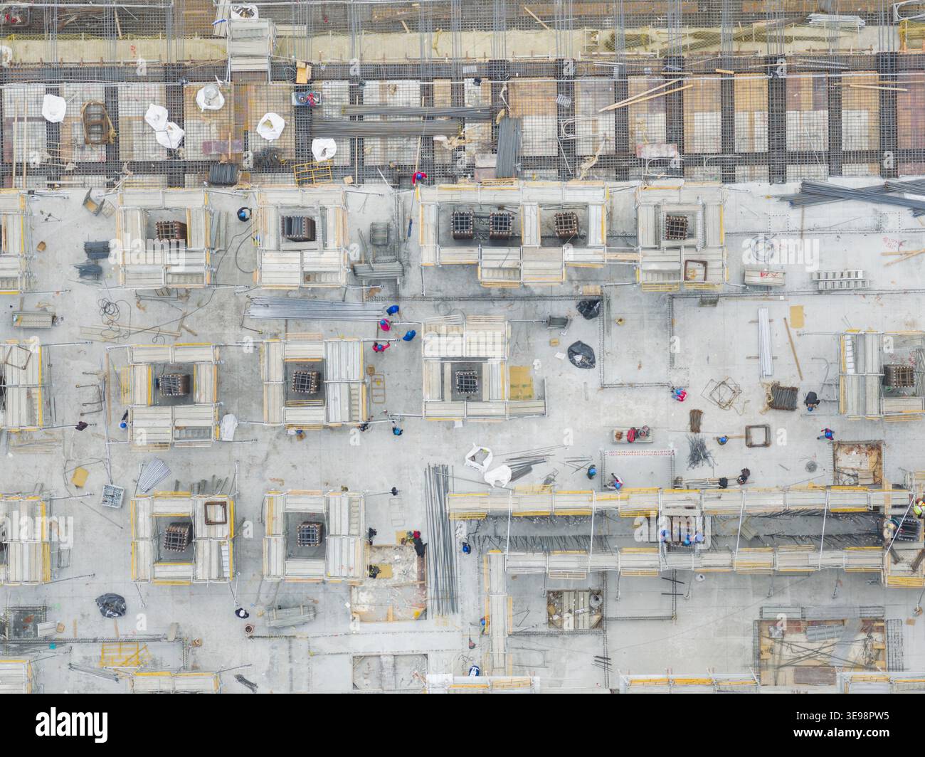 Aerial view of a top down construction site with workers, scaffolding, and concrete foundations in Taiwan. Stock Photo