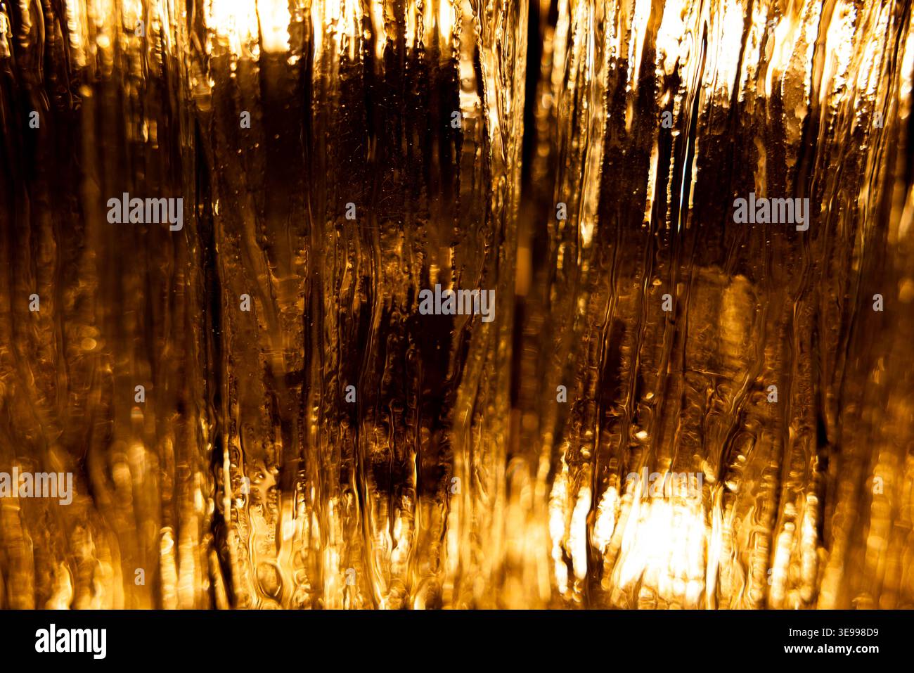 Abstract golden light through textured glass surface Stock Photo