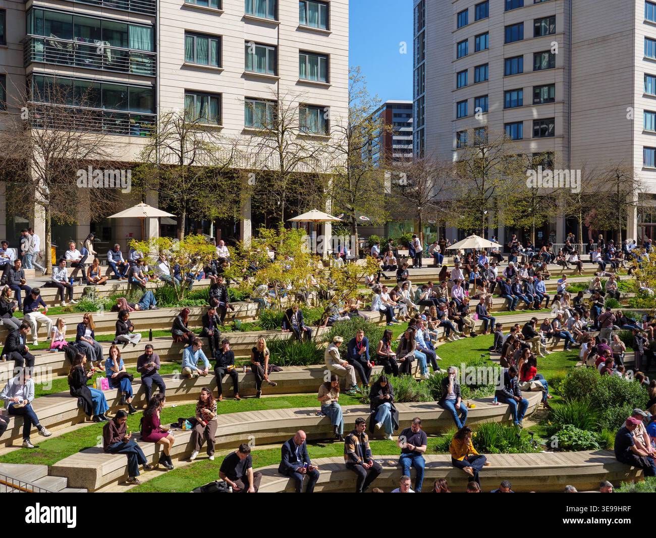 Office workers taking lunch break outdoors on a sunny day at Paddington Central, London, UK Stock Photo
