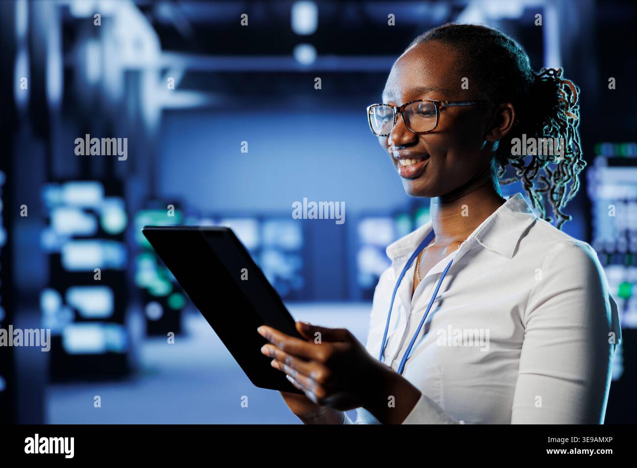 Smiling woman between server hub rows providing processing resources for businesses worldwide. Happy admin fixing data center mainframes tasked with managing massive databases Stock Photo