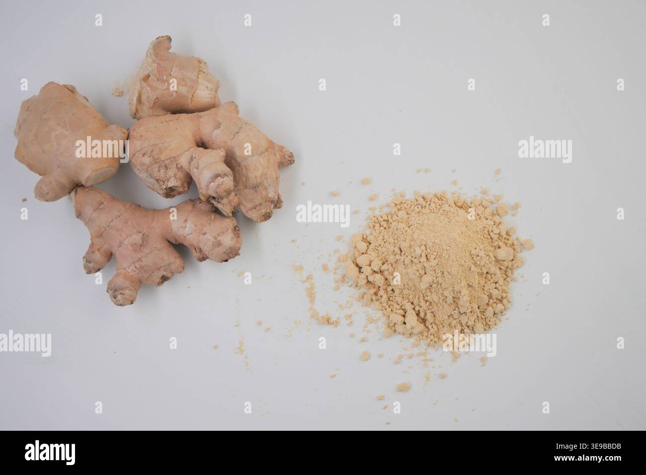 Ginger root and ginger powder displayed on a white surface Stock Photo