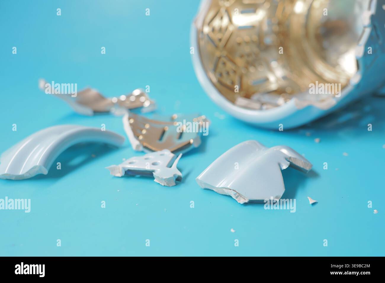 Broken pottery pieces on blue table surface Stock Photo