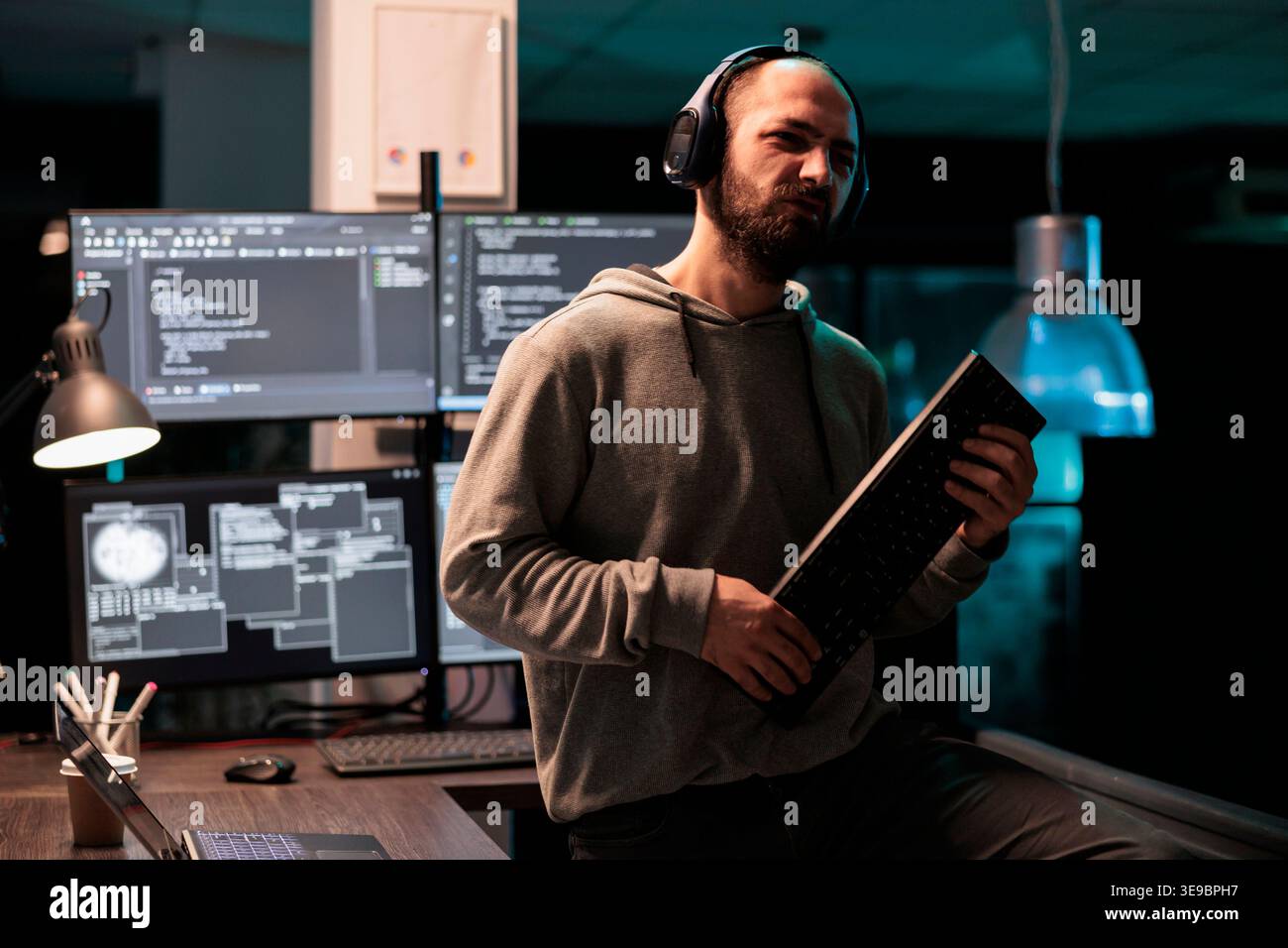 Cheerful developer fooling around with keyboard playing guitar, working on user interface with multiple screens parsing algorithm in software agency. Writing code and programming server. Stock Photo
