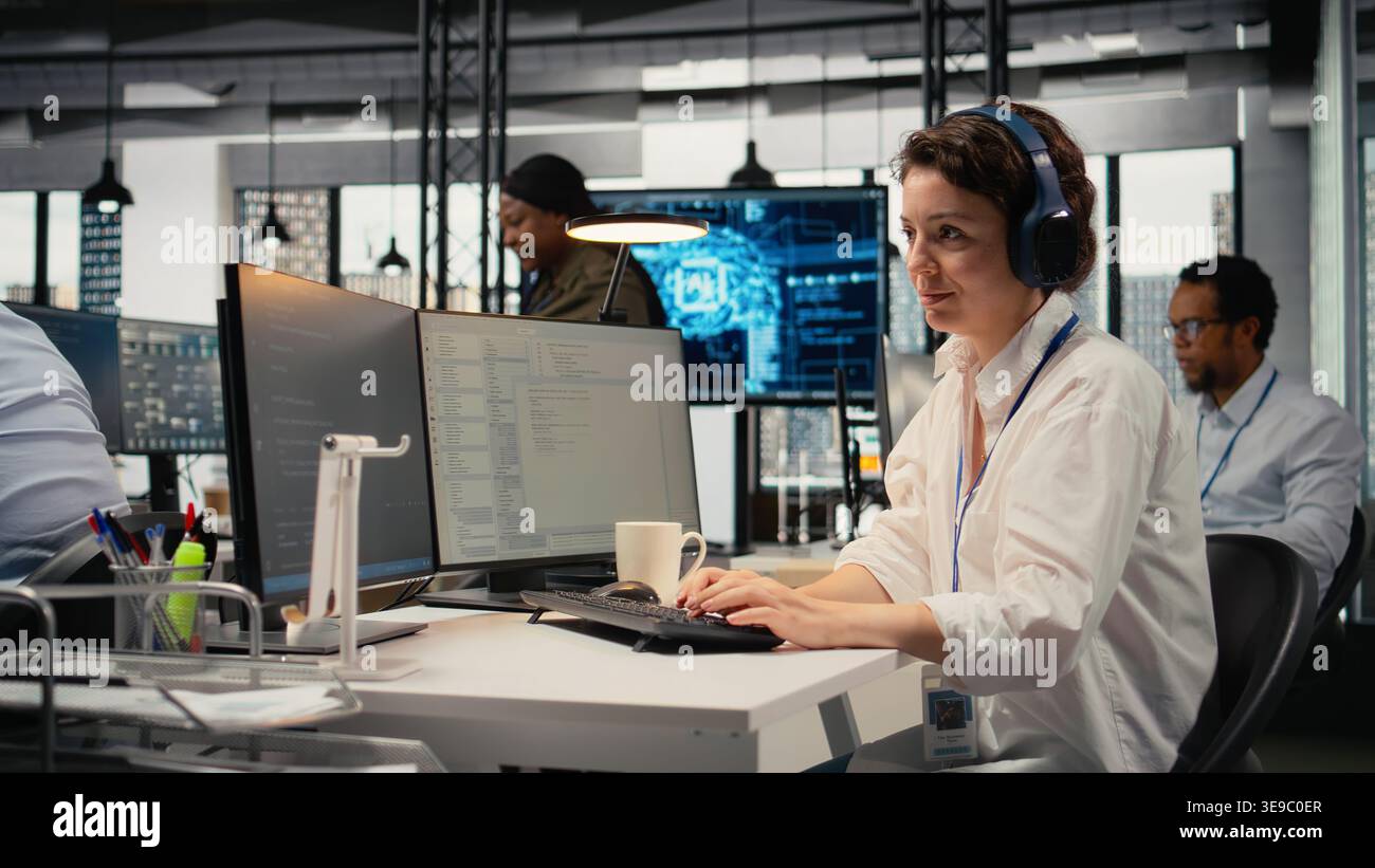 Developer listening music while working in AI startup training predictive models for language processing tasks. Tech expert wearing audio headphones uses technical expertise for IT tasks, camera A Stock Photo