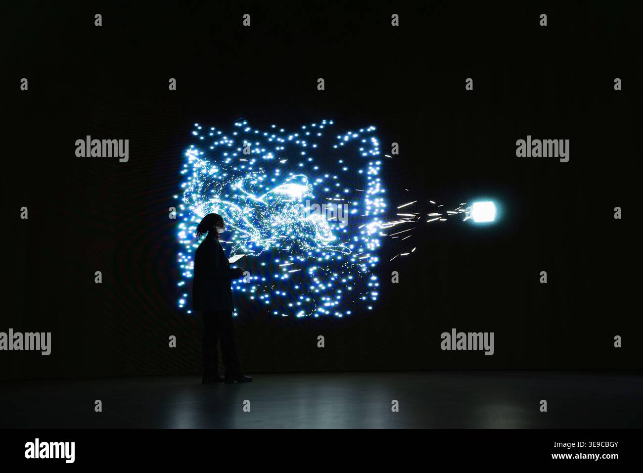 Programmer monitoring AI system cognitive flow using visual interface. IT professional studies real time activity of neural network nodes on digital wall to understand data processing algorithms Stock Photo