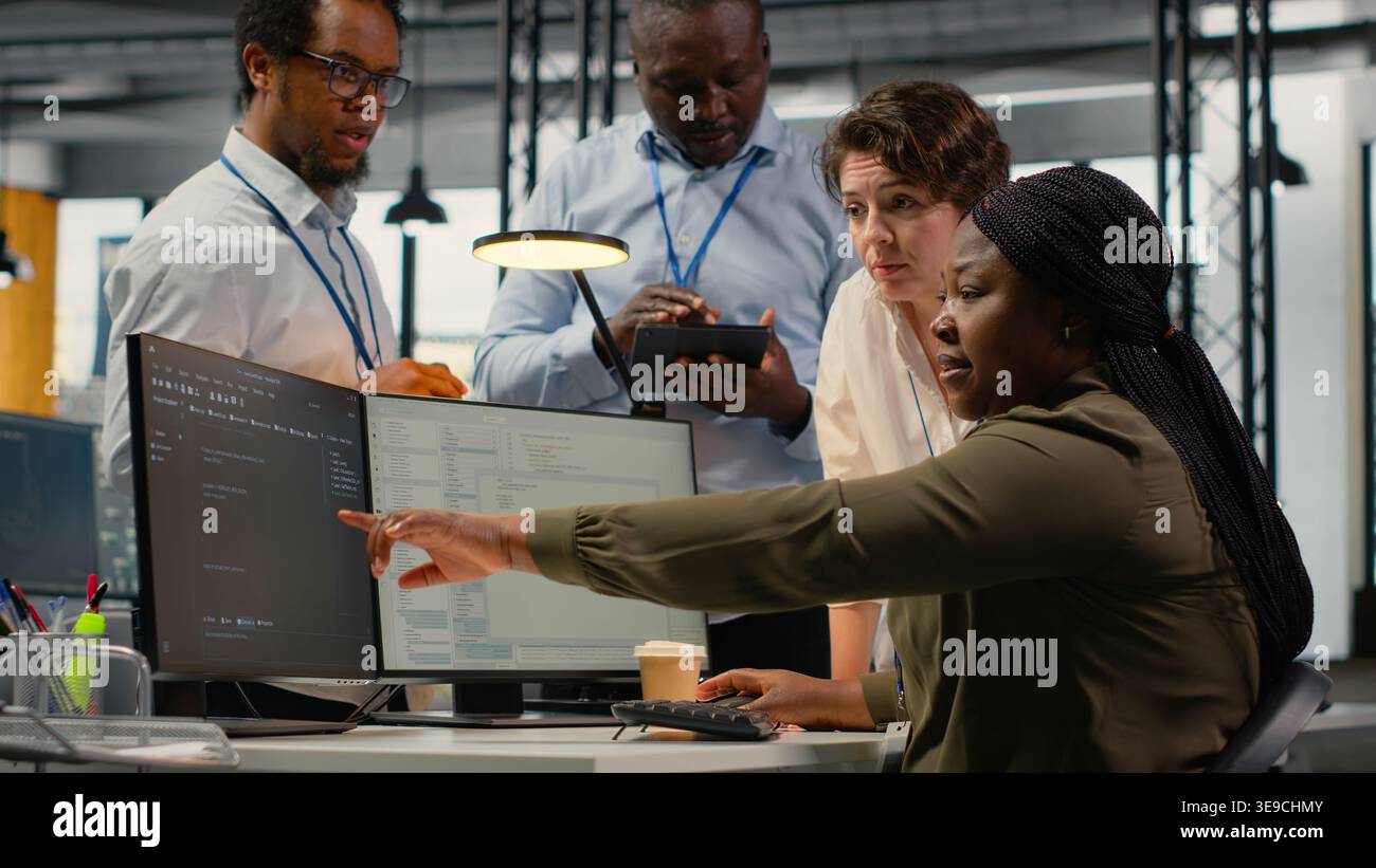 Team of software developers in office working together, automating workflows using AI. IT experts brainstorming to refine deep learning computational models for faster processing, camera B Stock Photo
