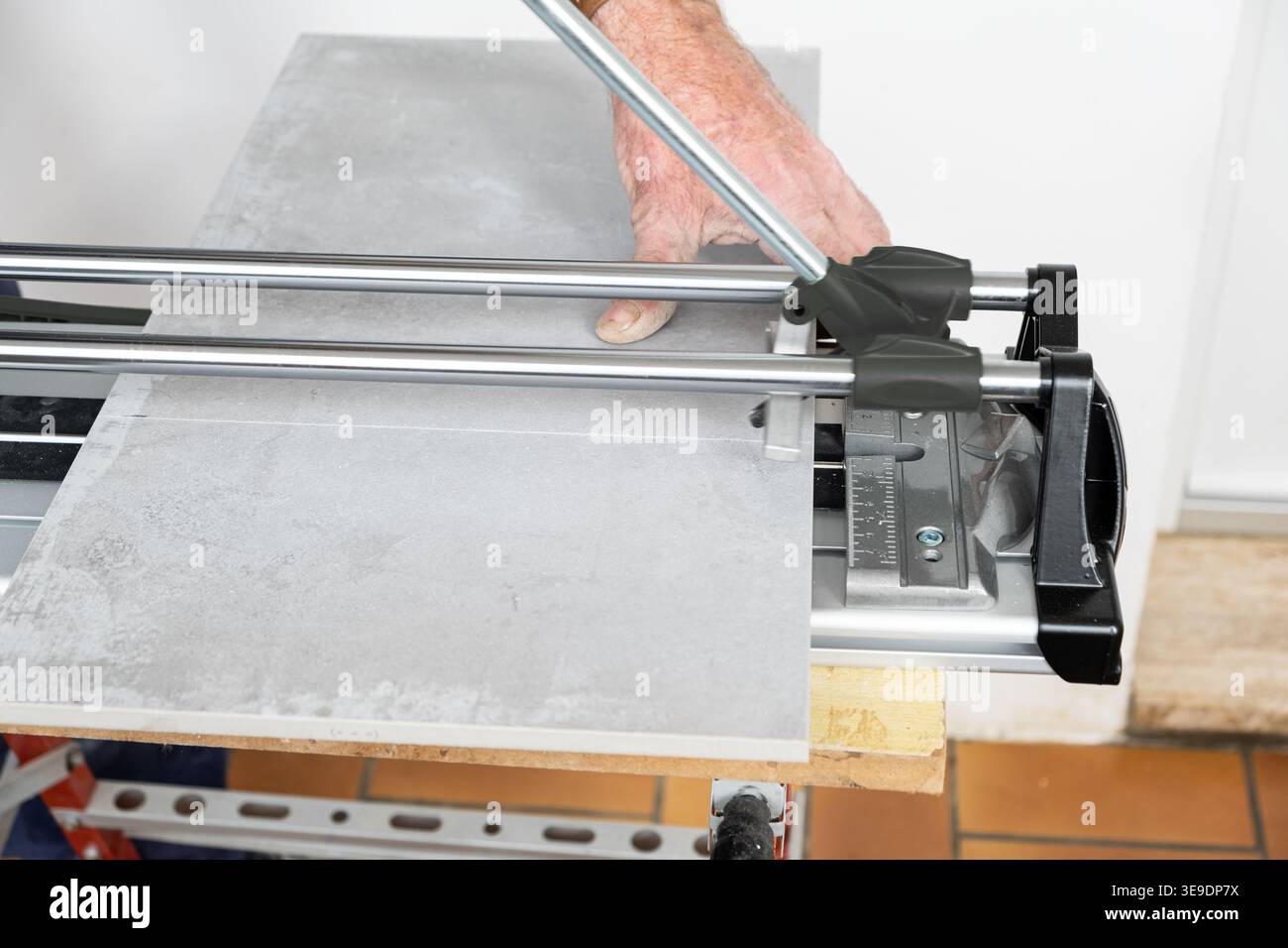 the mason cuts a ceramic tile with a tile cutter Stock Photo