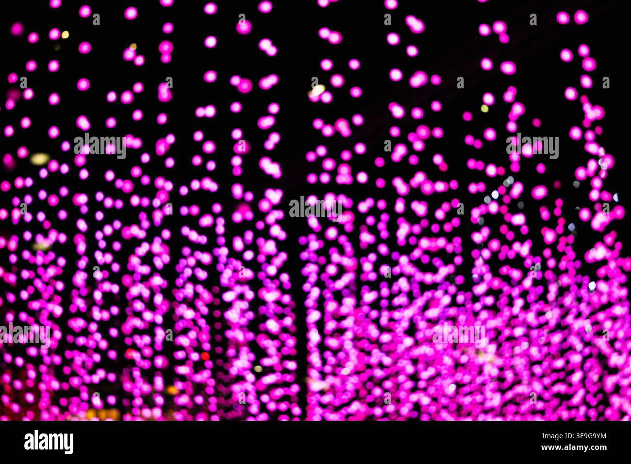 Abstract pink bokeh lights cascading on a dark background Stock Photo