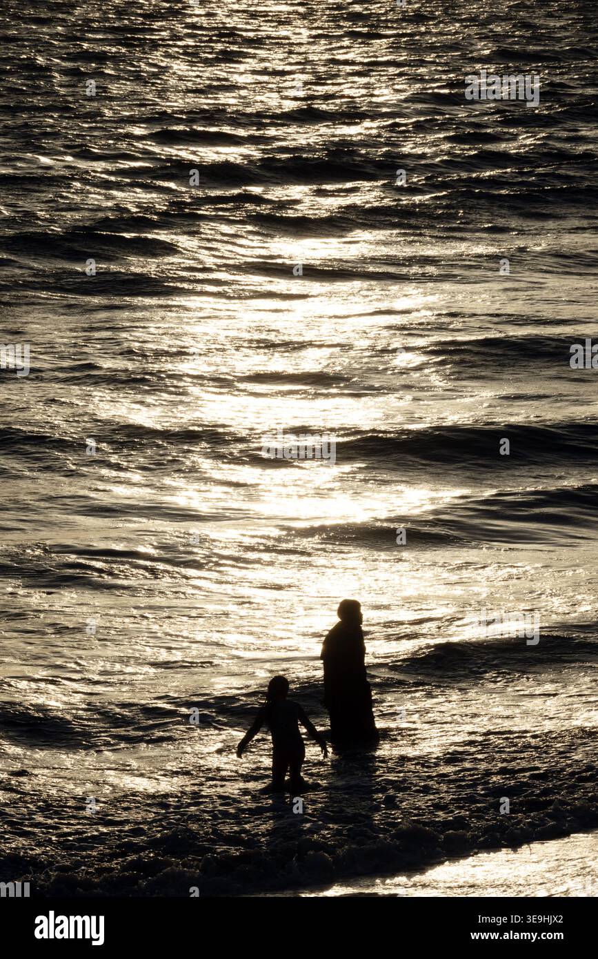 Silhouettes of people wading in ocean at sunset, Santa Monica, California, USA Stock Photo