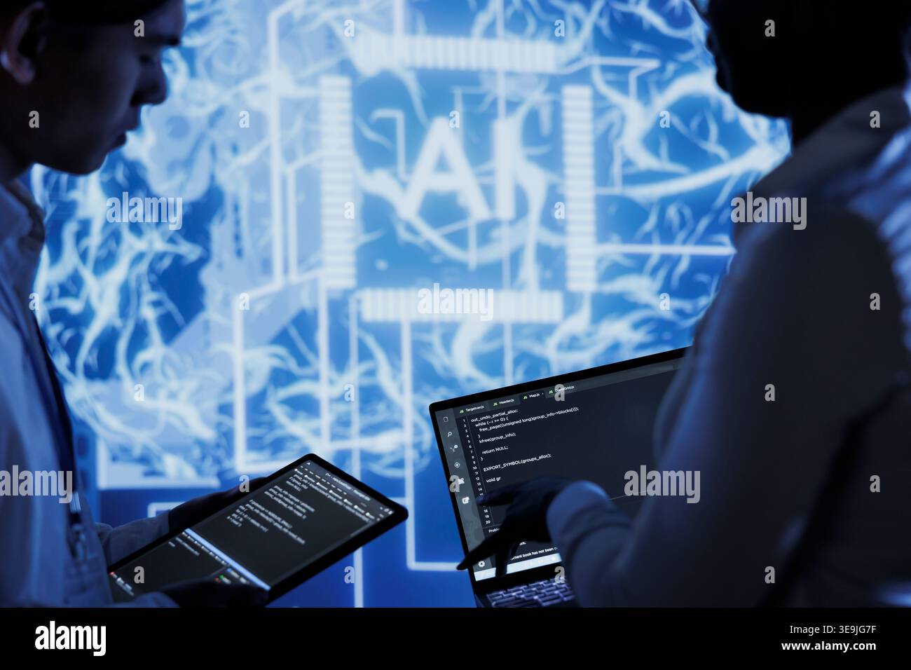 Hardworking colleagues write code on tablet and laptop to visualize artificial intelligence neural networks using augmented reality. Teamworking coworkers run AI script for information processing Stock Photo