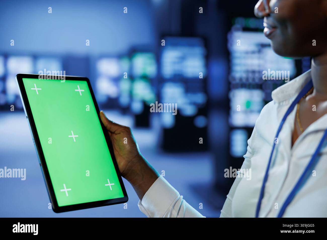 Trained technician in server room using mockup tablet to future proof network from downtimes and unexpected system failures. Expert with isolated screen device ensuring increased data security Stock Photo