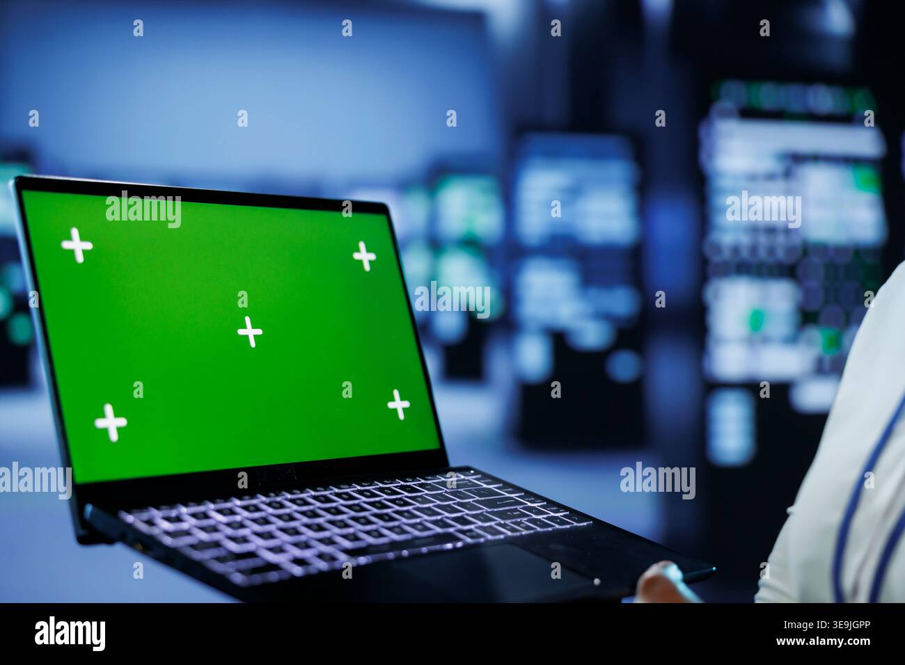 Admin in data center uses mockup laptop to prevent server machines overload. Expert between server mainframes using isolated screen device to ensure enough network bandwidth for smooth operations Stock Photo