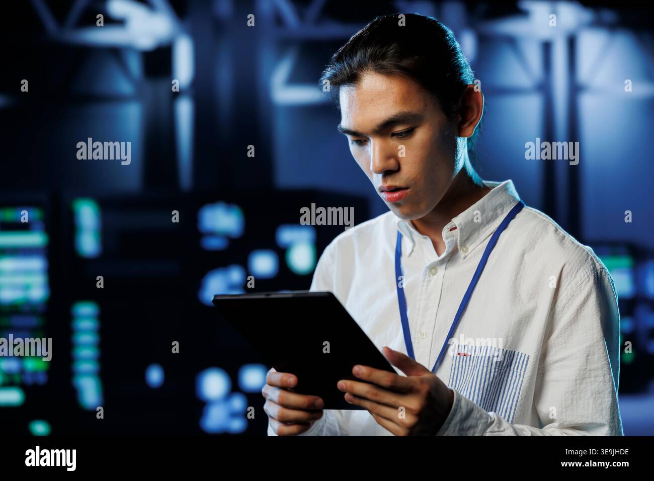 Tech support worker between server room equipment providing processing resources for businesses worldwide. Skillful developer fixes data center supercomputers used for managing massive databases Stock Photo
