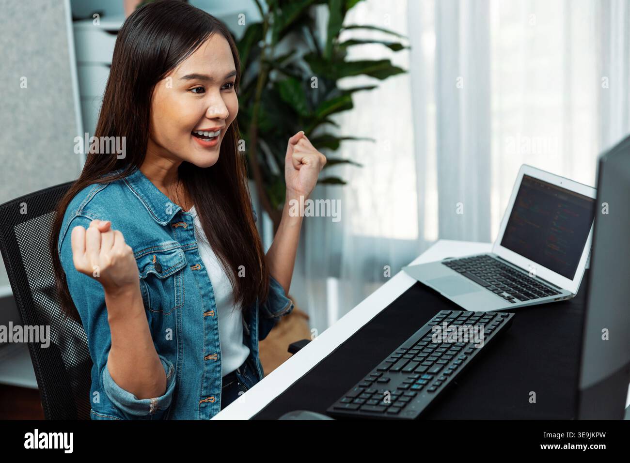 Smiling young Asian IT developer with happy face getting new software development information project with customer looking on pc screens, creating Stock Photo