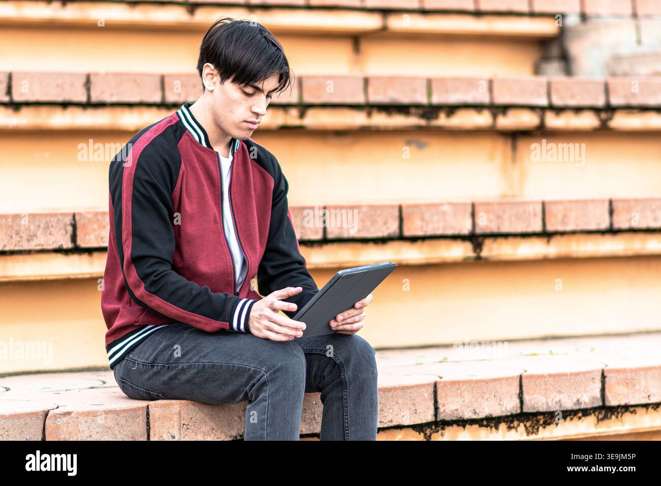 Young man studying digital tablet on steps Stock Photo