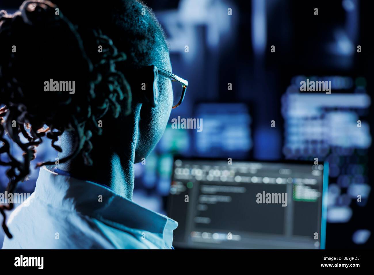 Trained admin running code and programming on laptop, troubleshooting and upgrading high tech facility designed to accommodate multiple rows of fully operational server racks Stock Photo