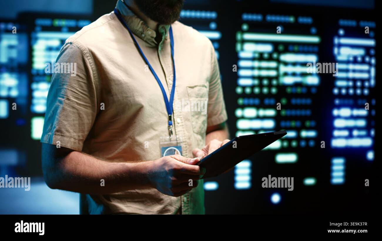 Experienced engineer inspecting operational server racks in computer network security data center. Supercomputers providing processing and memory resources for different workloads Stock Photo