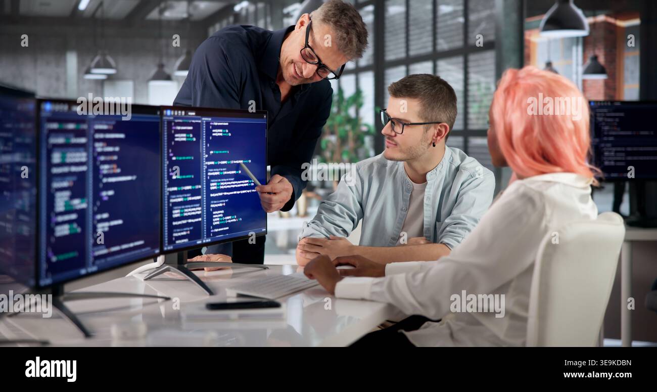 Software Engineer Coding On Computer While Collaborating With Diverse Team. Stock Photo