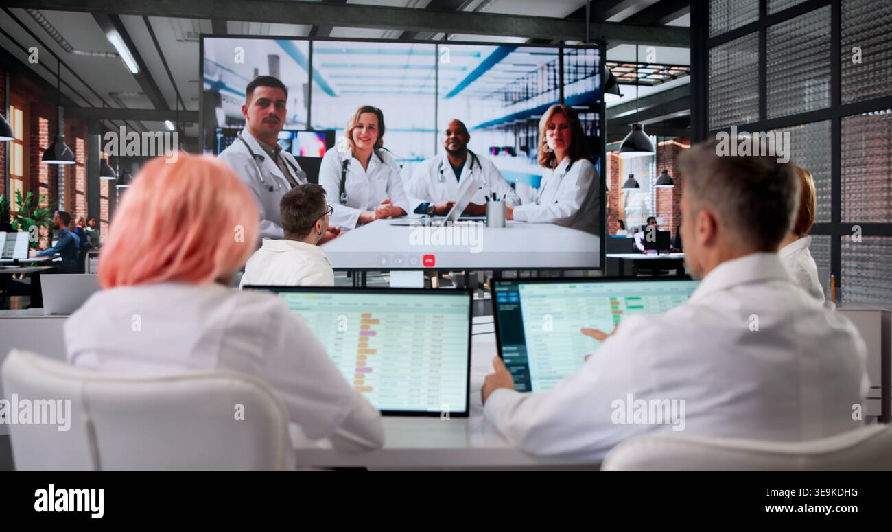 Doctor Leads Medical Conference Webinar While Nurses Watch Attentively On Screen. Stock Photo