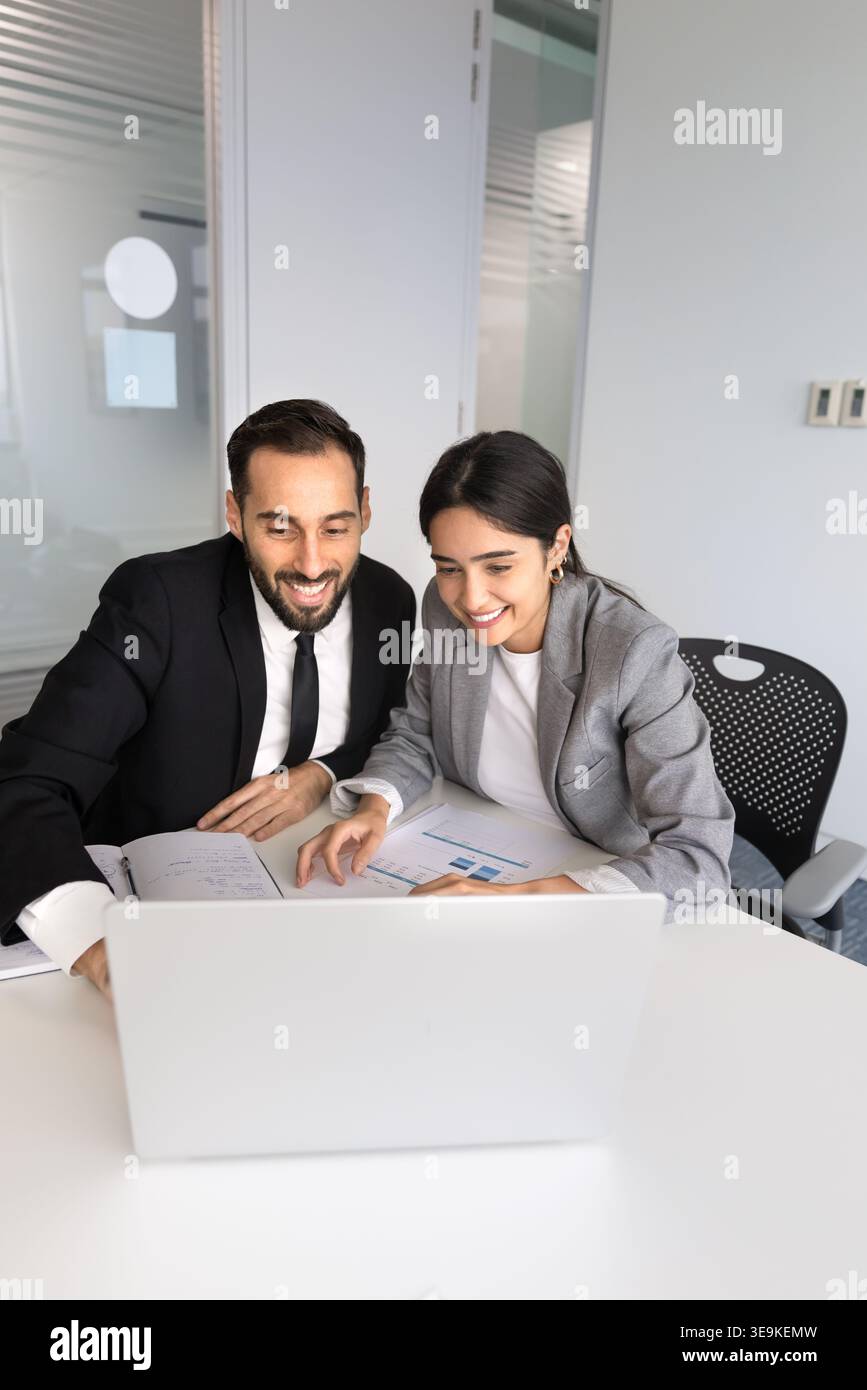 Smiling multiethnic colleagues collaborating on project using laptop Stock Photo