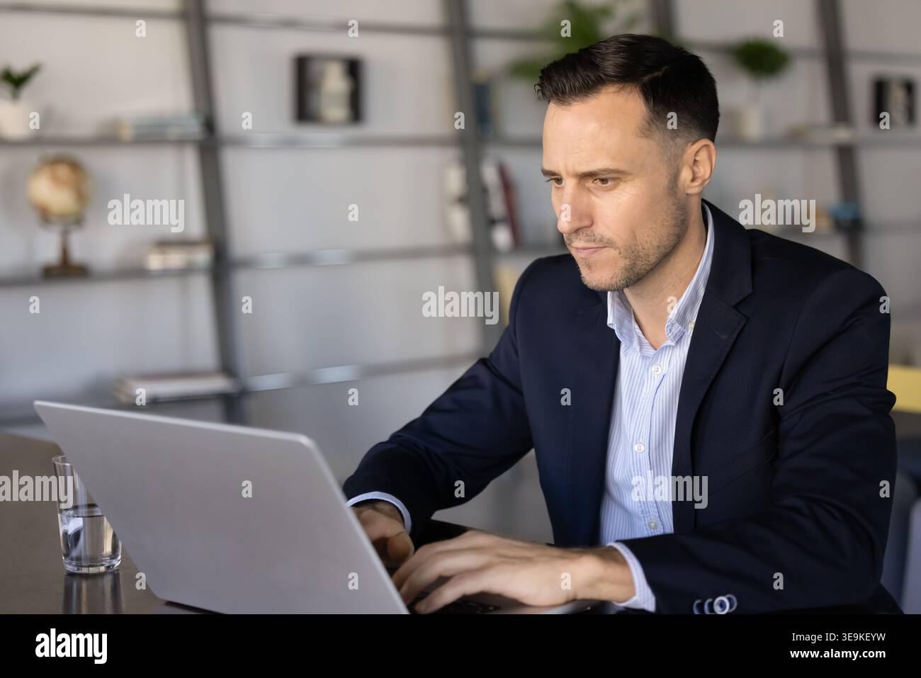 Focused businessman working on laptop at office desk Stock Photo