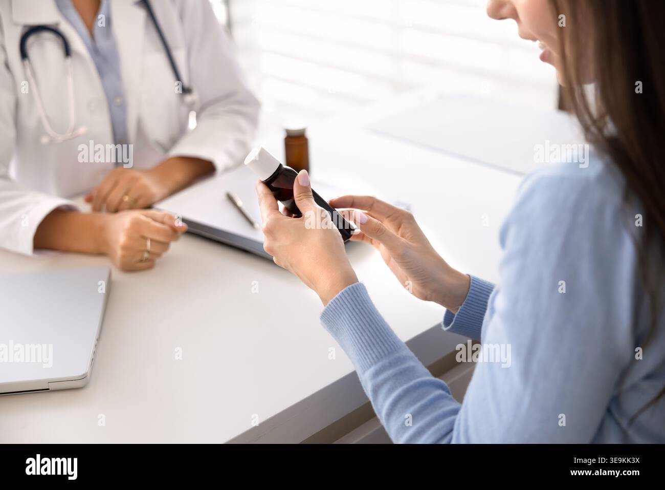 Closeup of patient holding pill bottle while doctor provides instructions Stock Photo