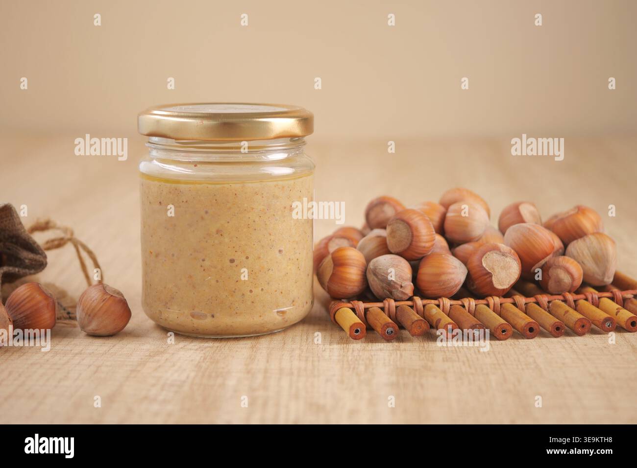Hazelnut spread in jar with hazelnuts on wooden table Stock Photo