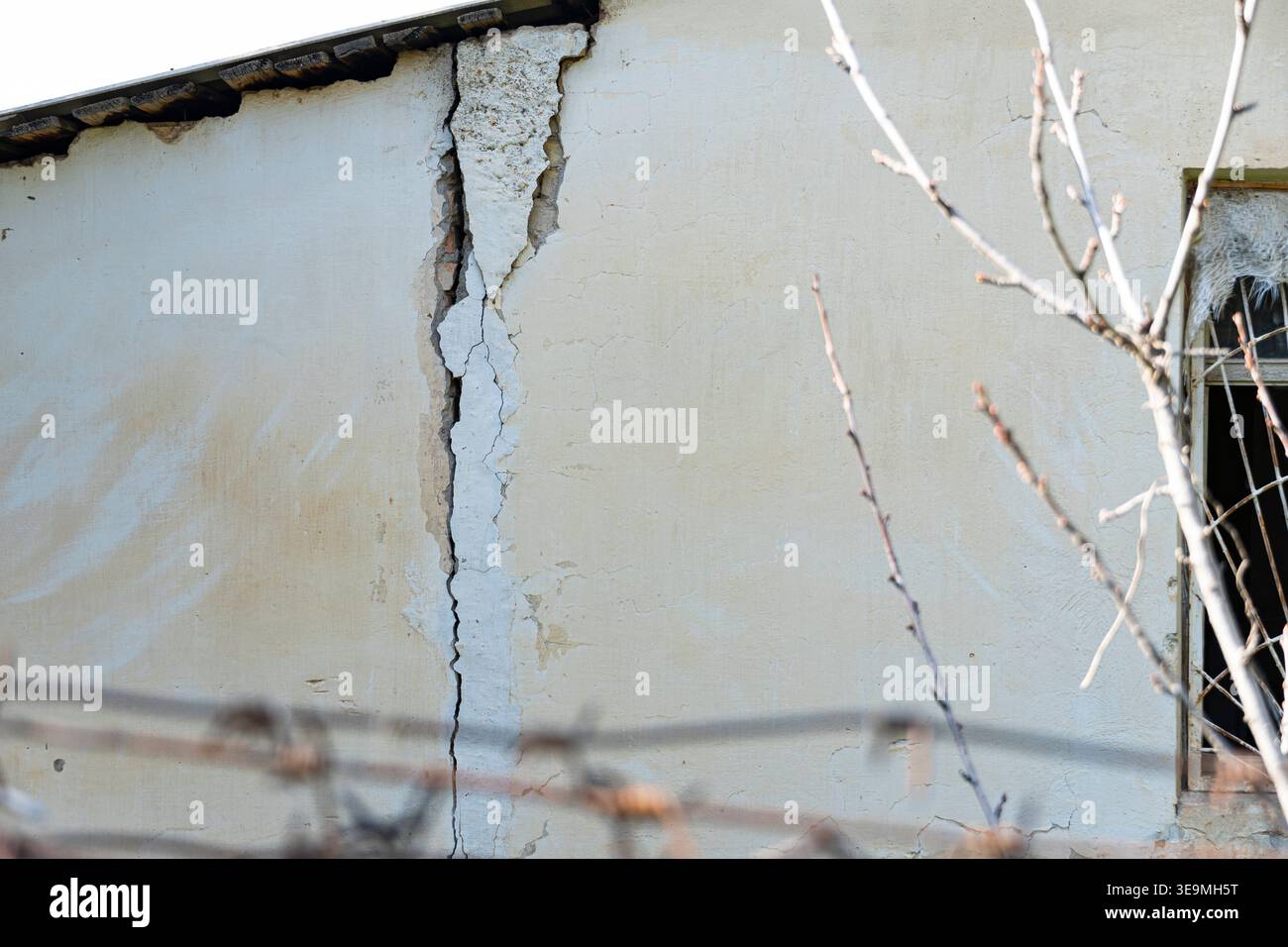 Deep crack in an old plaster wall of a damaged building. Concept of structural failure, poor maintenance, earthquake damage, or need for repair and re Stock Photo