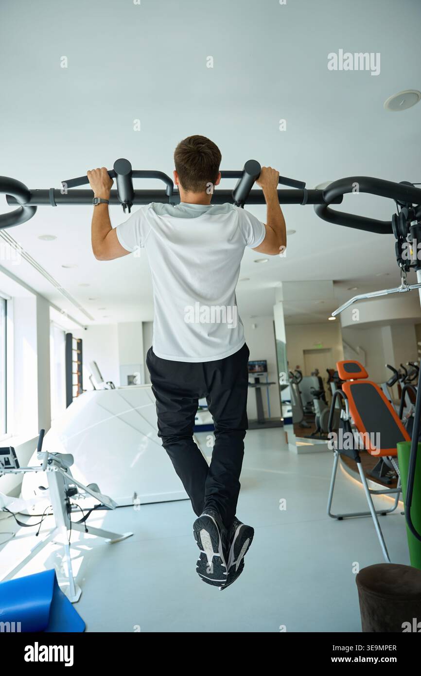 Focused man doing pull-ups in modern indoor gym Stock Photo